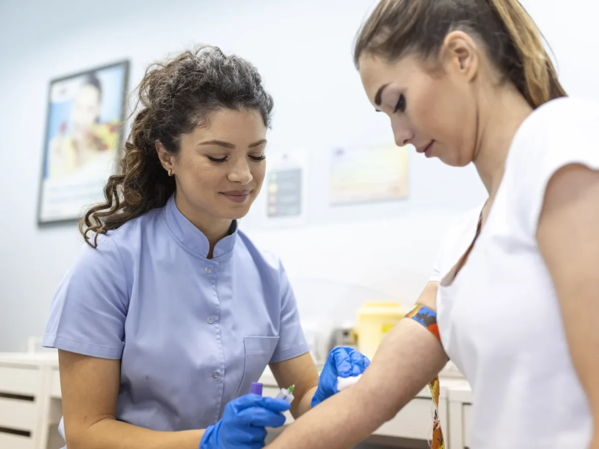 Profissional de laboratório atendendo uma paciente durante a coleta