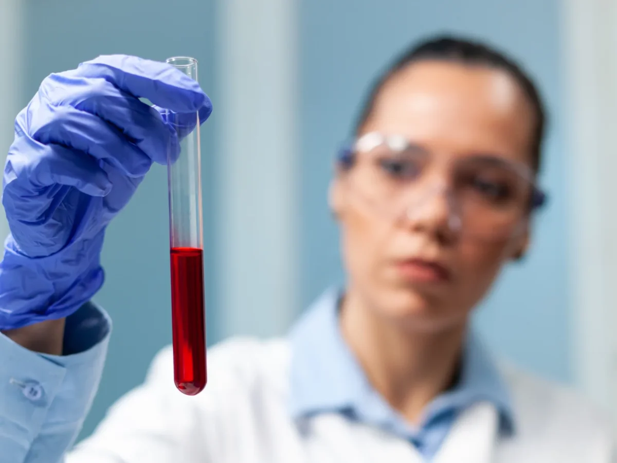 Profissional de laboratório segurando um tubo com amostra de sangue